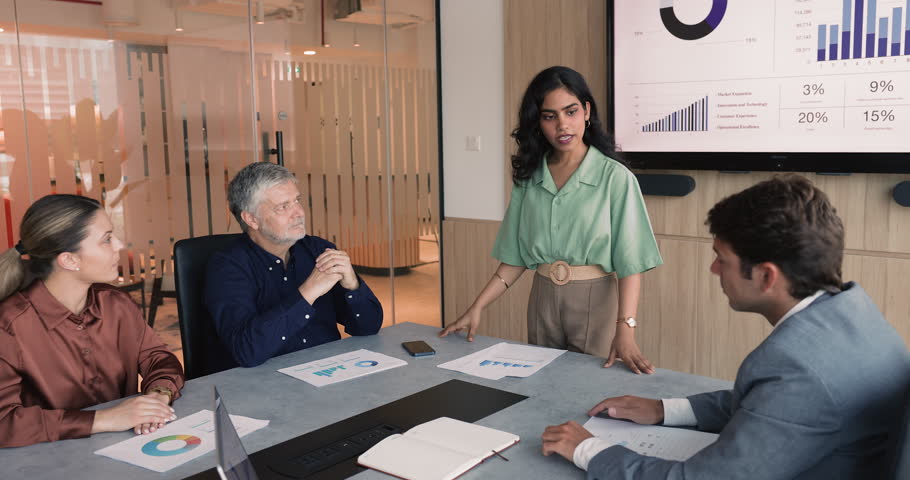 Diverse business team with young female project leader discussing ideas for development, successful marketing strategy. Senior manager offering solution, giving fist bump to younger boss