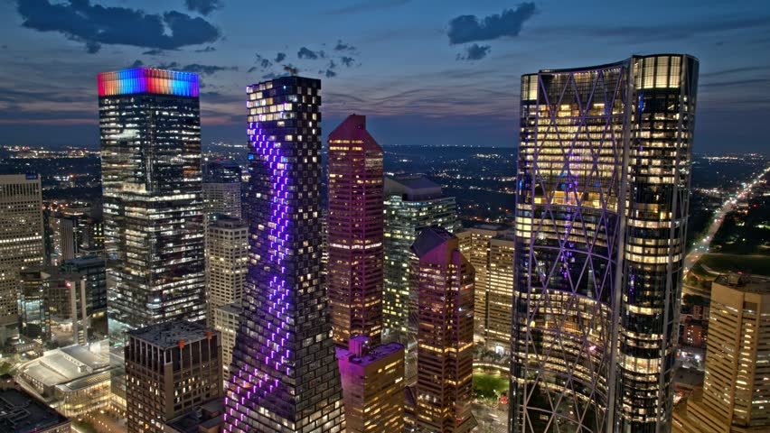 Dynamic aerial footage of Calgary cityscape at night. Illuminated skyscrapers and Calgary tower create a vibrant urban panorama. City lights gleam below.