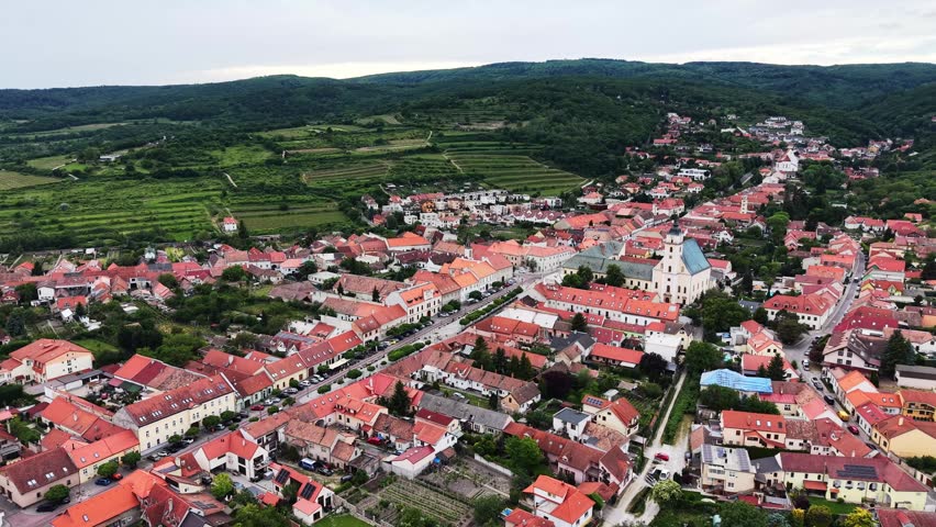 Drone footage of the historic town of Svaty Jur surrounded by vineyards and rolling hills of the Little Carpathians in western Slovakia.