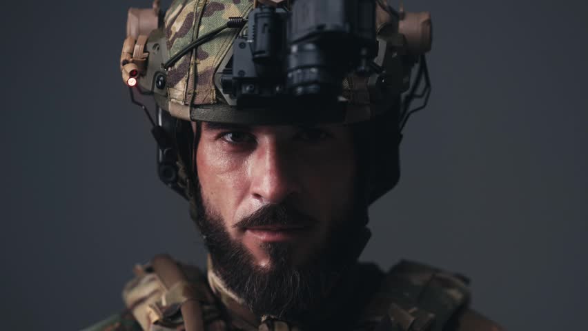 Young soldier in tactical gear smiling confidently while standing on duty. Concept security, protection and military service.

