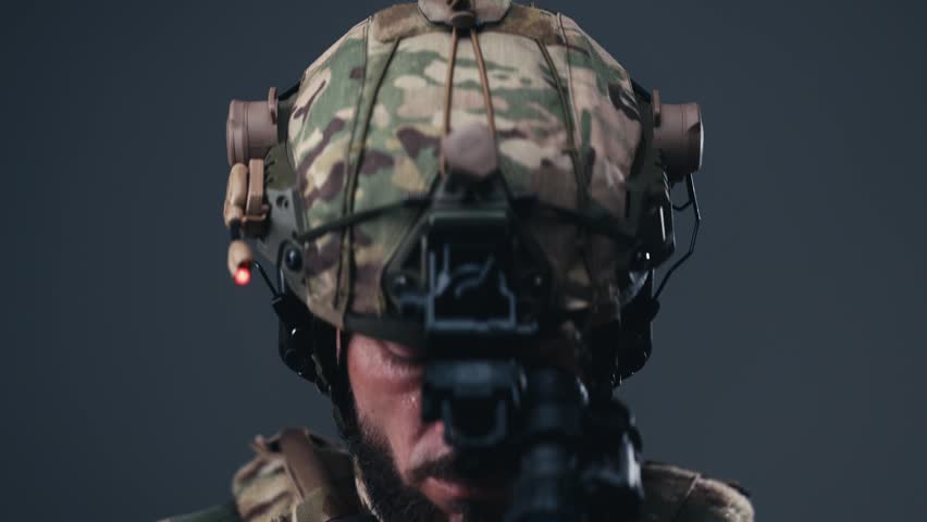 Male fighter in tactical combat equipment displays a serious expression while wearing a helmet with night vision gear, emphasizing modern military technology