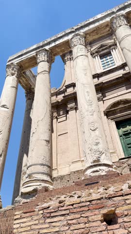 Panoramic aerial view of the Roman Forum in Rome featuring ancient columns, triumphal arches, temple ruins, the Vittoriano monument, and tourists under a clear blue sky.