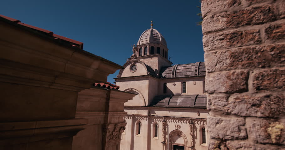 View of the dome and facade of St James Cathedral in Sibenik Croatia framed by historic stone buildings.