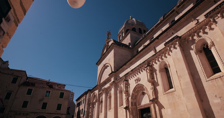 Low angle view of the facade and dome of St James Cathedral in Sibenik Croatia under a clear blue sky.