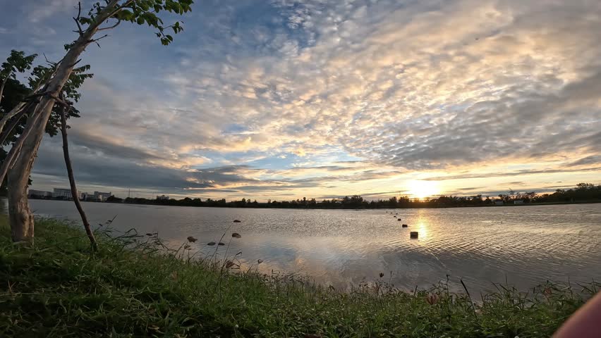 Time lapse video of clouds drifting over a lake at sunset.
