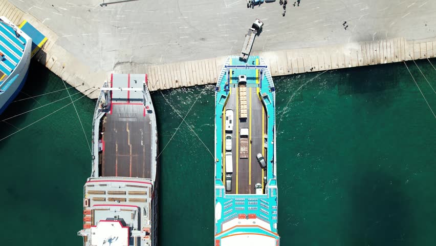 Large truck maneuvering off a roll-on roll-off ferry docked at the harbor pier