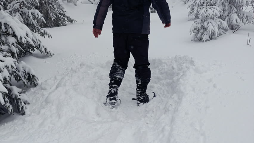 Close up of winter boots digging a trench in deep forest snow