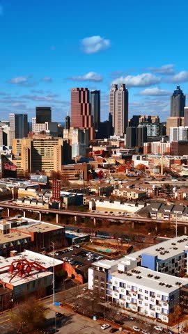 Dynamic aerial view of Atlanta Georgia cityscape, towering skyscrapers, busy highways, and urban development, sunny day.