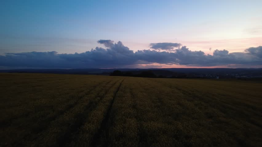 Aerial drone view of rural fields at dusk. Peaceful countryside landscape with evening sky, farmland and distant horizon in soft natural light.