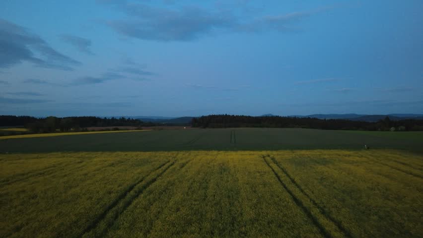 Aerial drone view of rural fields at dusk. Peaceful countryside landscape with evening sky, farmland and distant horizon in soft natural light.