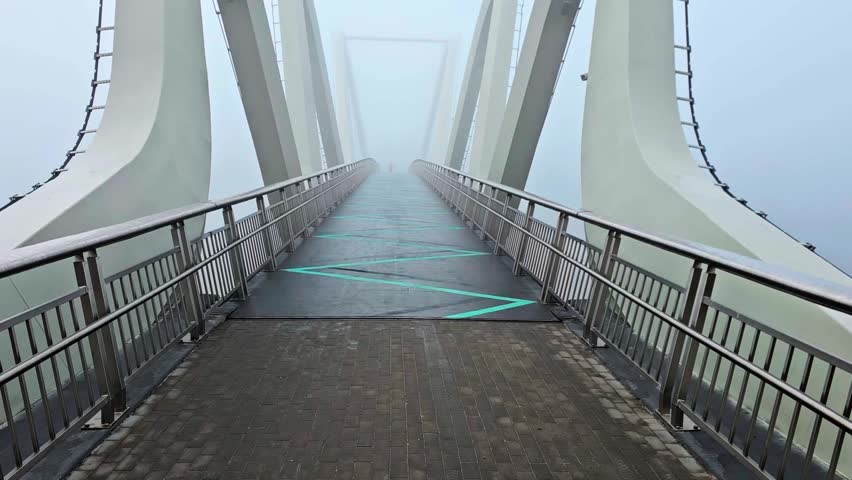 Symmetrical wide shot of modern pedestrian wave bridge disappearing into thick fog horizontal view. Kyiv, Ukraine Wave bridge