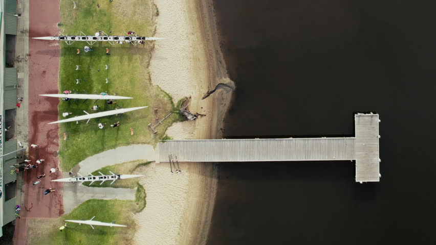 Aerial view of people carrying canoes at a rowing club near the water.