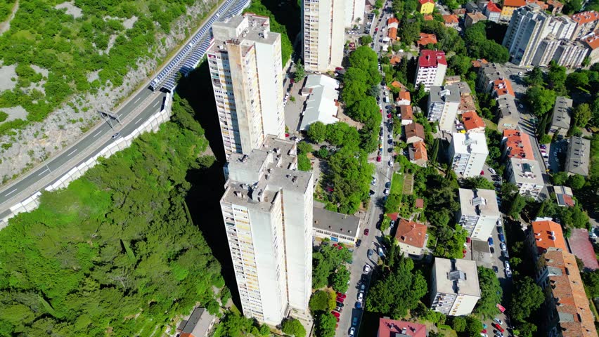 Aerial view of Rijeka, Croatia, showcasing its vibrant urban landscape nestled between lush green hills and the sparkling Adriatic Sea. A bustling port city. Skyscrappers on Banderovo