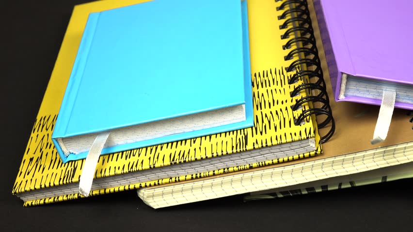 Various types of notepads lie on a black table. Objects for notations, studying, note -taking, and diary.