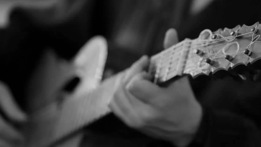 Cinematic monochrome acoustic guitar strings played by musician hands
