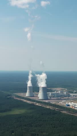 Smoking cooling towers at nuclear power plant. Aerial view. Vertical footage
