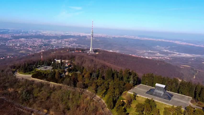 Aerial drone shot of Avala mountain ridge featuring telecommunication tower and Monument to the Unknown Hero in Belgrade, Serbia.