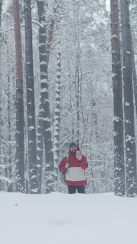 Snowy forest scene, Individual standing amidst snowcovered trees, Figure with red attire in icy forest setting
