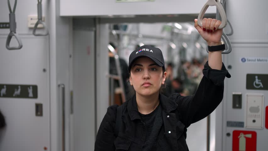 Woman holding a handrail while riding public transport in Seoul, South Korea