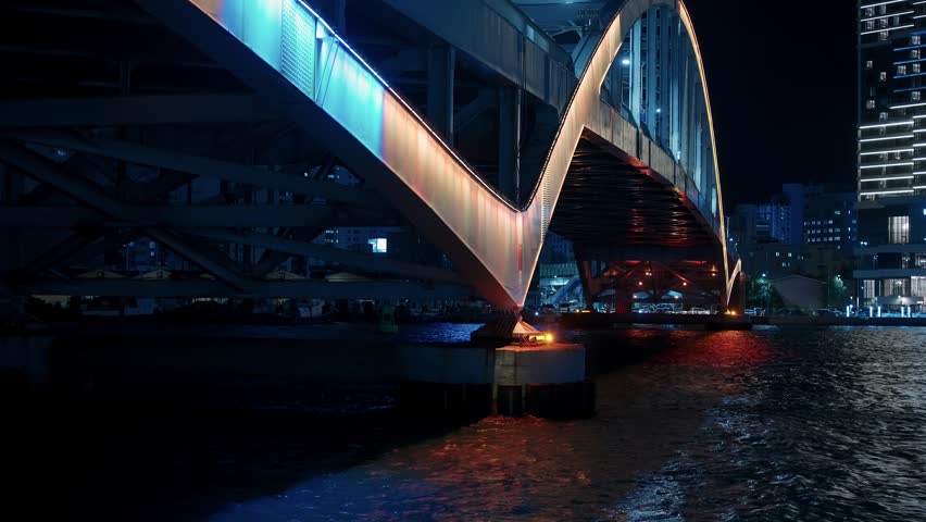 Bridge illuminated with colorful lights over water in Busan at night
