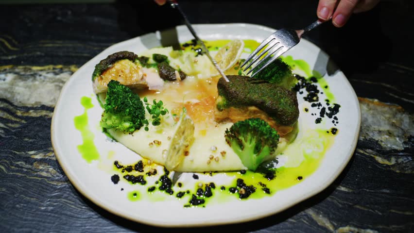 Close up shot person eating delicious salmon steak with broccoli and mashed potatoes in restaurant.