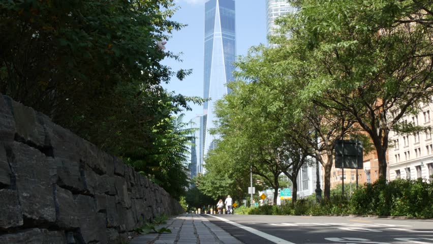 Lower Manhattan Downtown Financial District, New York City, United States. One World Trade Center skyscraper building, Freedom tower from Battery park. Summer trees greenery, West street perspective.