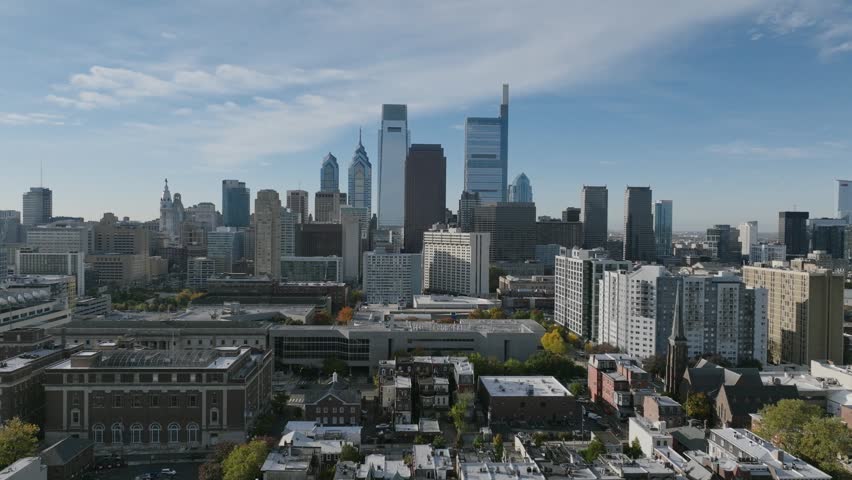 Dynamic aerial view of Philadelphia cityscape, featuring Comcast Technology Center, One Liberty Place, and surrounding urban architecture. Filmed in daylight.