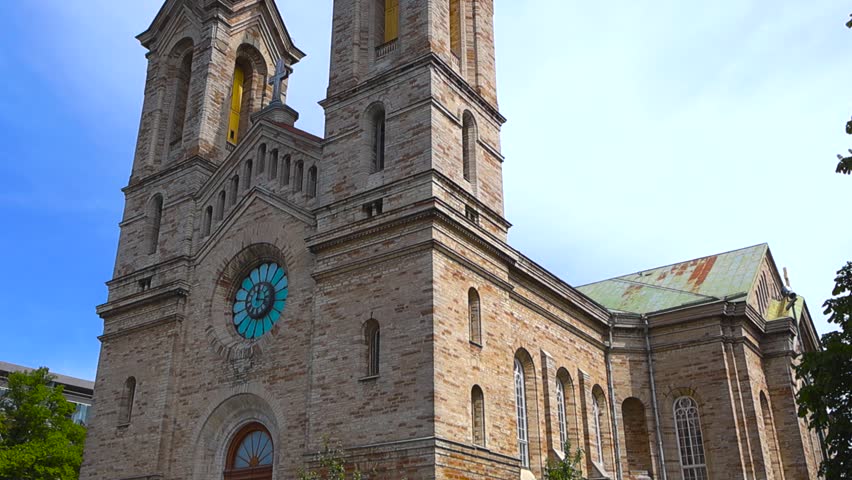 Majestic stone facade of the historic Kaarli Lutheran church in Tallinn, Estonia, standing against a bright blue sky on a sunny day, showcasing its twin bell towers and ornate windows
