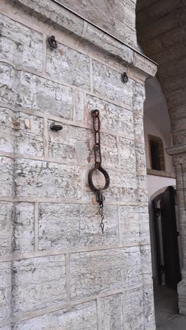 Historic iron shackle and chain, used for punishment, hanging on the limestone wall of the old Town Hall building in Tallinn, Estonia, a remnant from medieval times in the old town