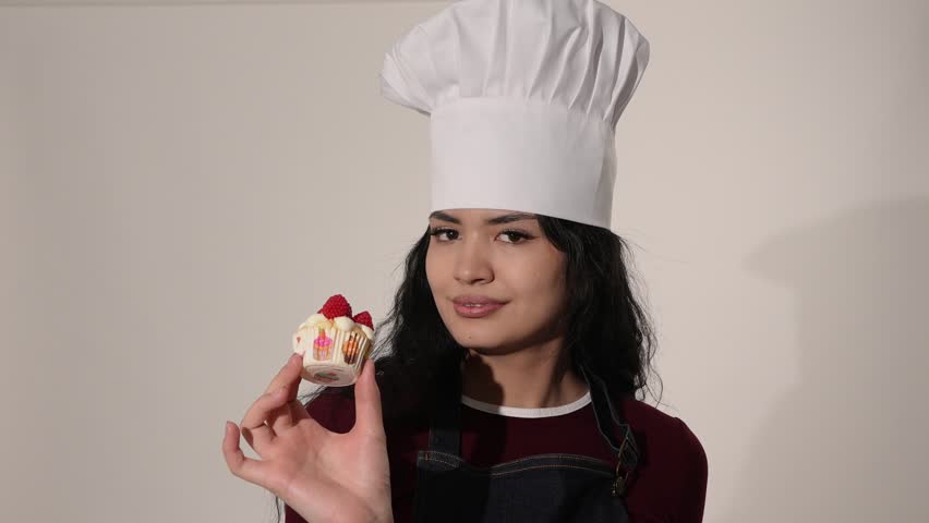 Professional pastry chef smelling a fresh raspberry cupcake