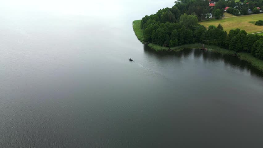 Serene Lake Scene with Motorboat Under Overcast Sky