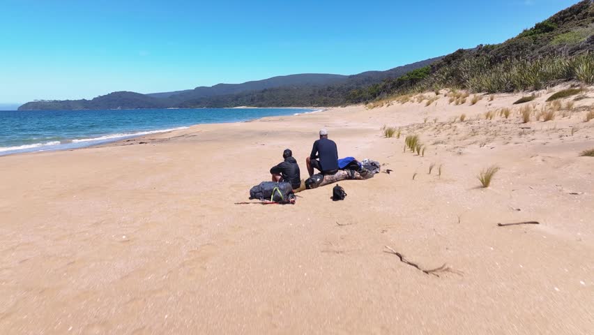 Hikers enjoying view at Murray Beach. Tropical remote place, Rakiura. Drone overhead.