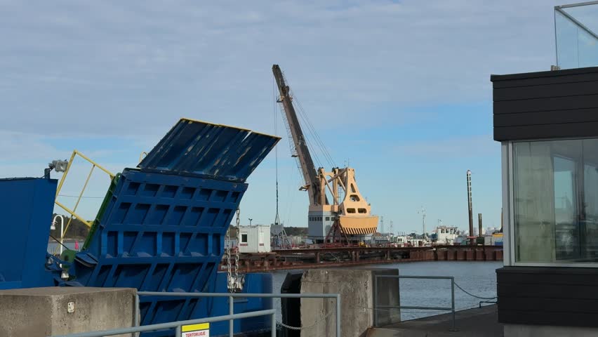 Open ferry ramp and harbor crane in the industrial port of Klaipeda.