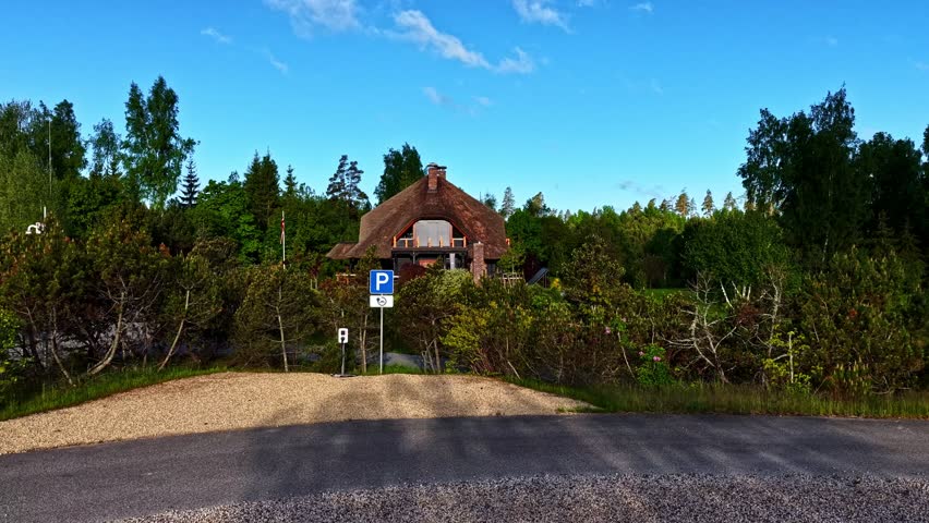 Cozy wooden cabin nestled in green forest under clear blue sky.