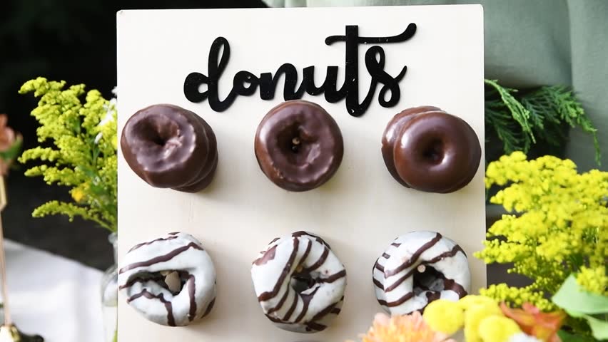 Donut shop display stand with rows of dark chocolate and white chocolate donuts daytime
