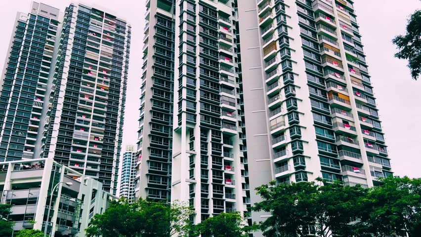 Aerial tilt-up view of Toa Payoh apartments in Singapore draped with national flags during National Day celebrations, showing vibrant residential blocks and patriotic city atmosphere. August 5, 2025. in Southeast Asia