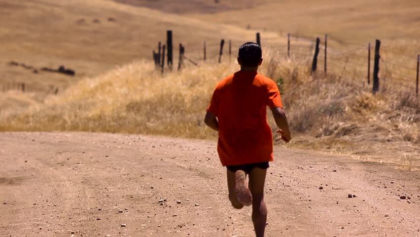 Marathon runner training on dirt road on a hillside