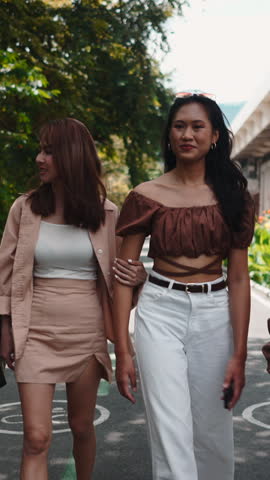 Two stylish asian women walking and talking in a city park