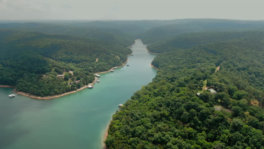 Aerial sweep over Beaver Lake in Arkansas, showing winding blue water and dense summer foliage. Lush landscape for travel and nature documentaries.