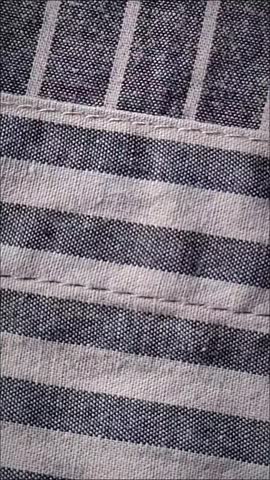 Close-up view of a striped casual shirt featuring fabric texture, buttons, and pocket details. Fashion apparel background with minimalist design, textile pattern, tailoring concept, and clothing industry theme. Suitable for fashion, garment, retail, and textile-related projects.