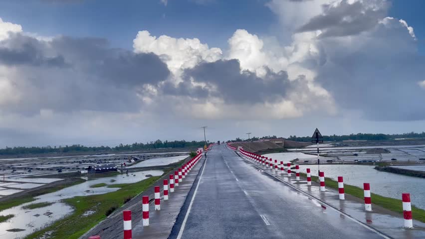 Beautiful countryside road after rain, clear blue sky, fresh weather, and traditional salt farming alongside a clean wet road. driving on the road.