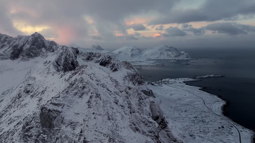Snowy coastal mountains and fjord at sunrise with scattered islets