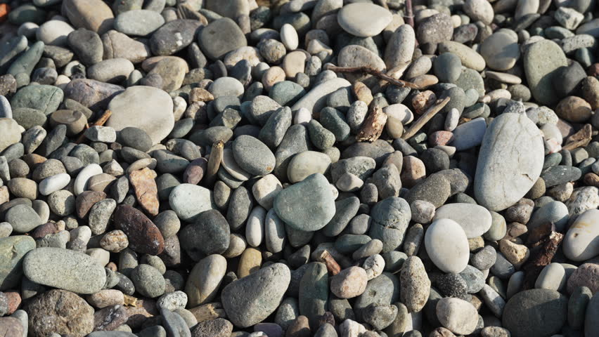 Small gravel falls onto pebbles on the beach. Small stones fall as construction gravel