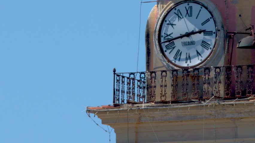A static close-up shot of an ancient clock tower against a clear blue sky.