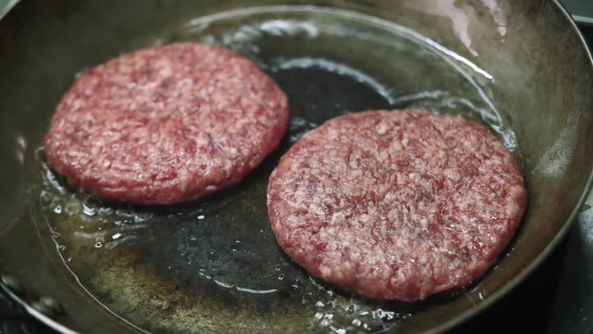 Frying patties. Cooking process. Meat meal preparing in hot bubbling oil on skillet for tasty burger. Appetizing fast food service.