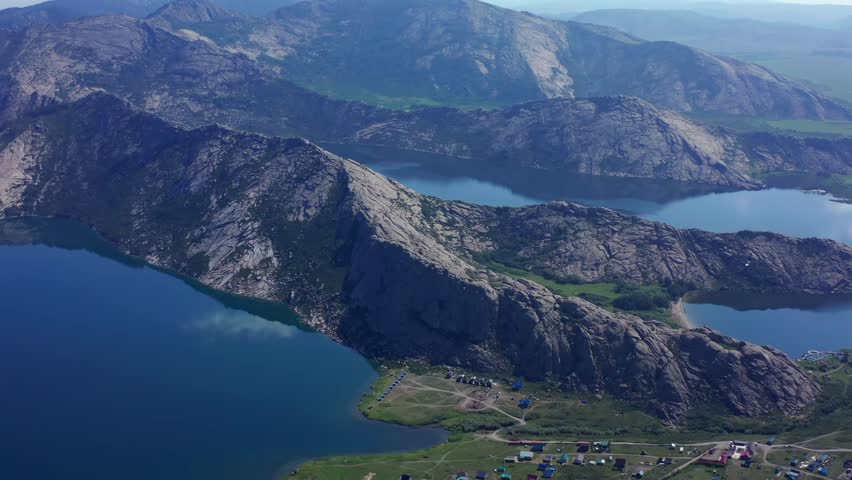 Aerial panoramic view over the Kokshetau lakes system including Shalkar lake in North Kazakhstan, revealing mountain ridges, multiple connected lakes, steppe valleys and remote natural landscape.