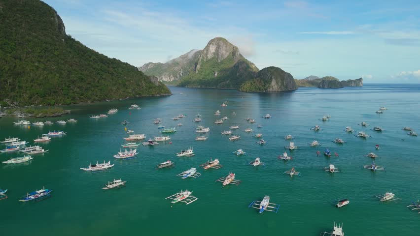 Hundreds of bangka tour boats moored in El Nido bay with iconic Cadlao Island peak rising behind lush green islands and scattered archipelago