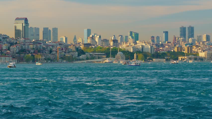 Panoramic view of the Istanbul city skyline across the blue Bosphorus sea under a clear sky during golden hour in Turkey