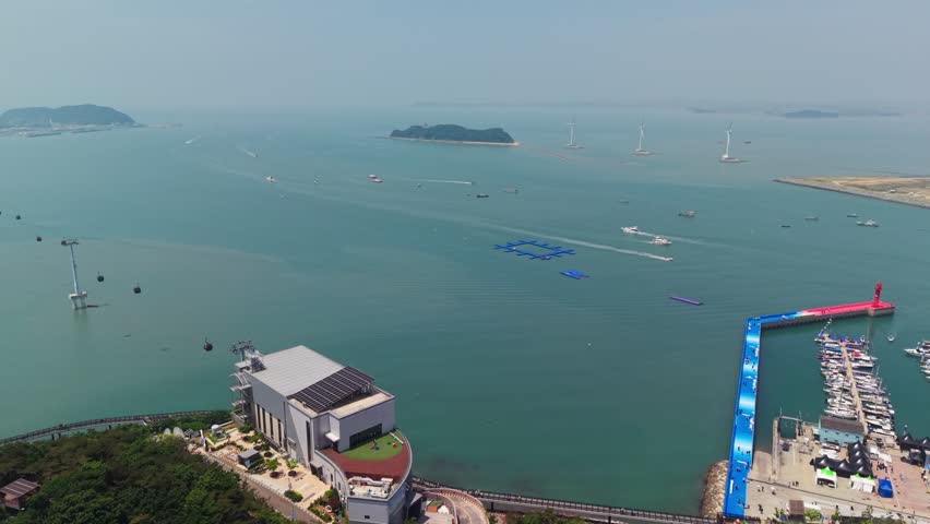 Aerial parallax around Jebudo Marine Cable Car Seohaerang Jeongok Station revealing busy crowded Jeongok Port marina during Hwaseong Boating Festival in South Korea