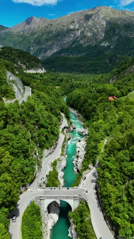 Aerial view of cars and people crossing old stone bridge over turquoise river gorge